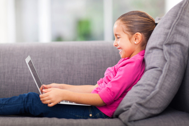 little girl using laptop on sofa - Φωτογραφία, εικόνα