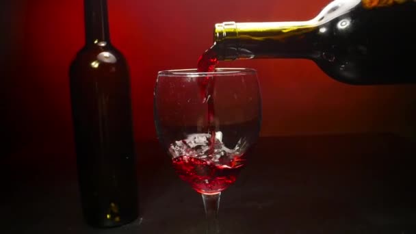 Red wine pouring into a wine glass on red background in slow motion - Filmmaterial, Video