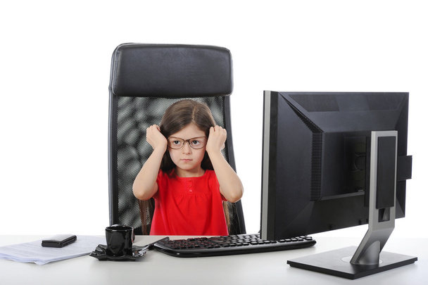 Little girl wears glasses at the table in front of a computer - Foto, imagen