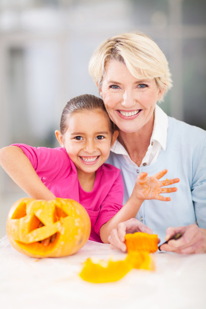 little girl and grandmother making halloween pumpkin - Foto, Imagen
