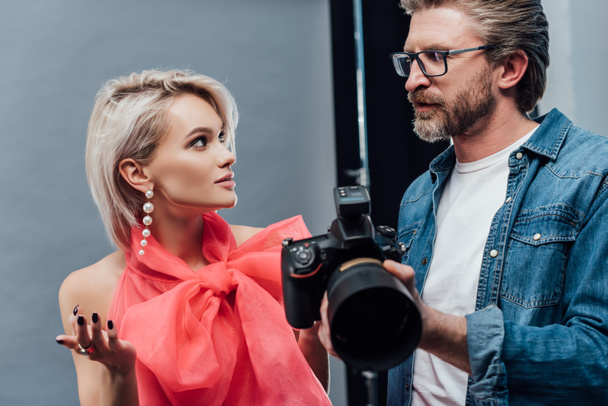 handsome art director holding digital camera and looking at attractive model  - Fotoğraf, Görsel