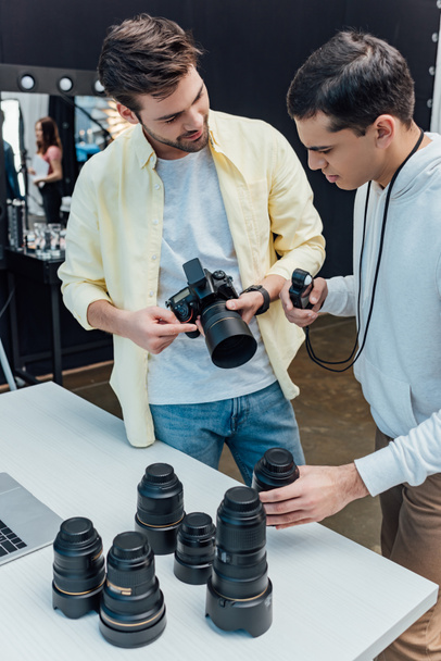 handsome art director standing near photographer and holding photo lens  - Photo, Image