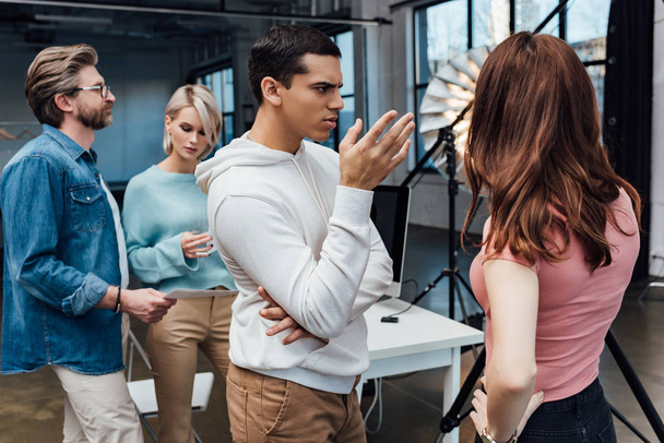 selective focus of man gesturing near art director and coworkers in photo studio  - 写真・画像