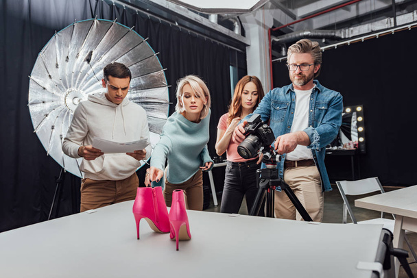 fotógrafo sesión de fotos zapatos de color rosa cerca de compañeros de trabajo en estudio de fotos
  - Foto, imagen
