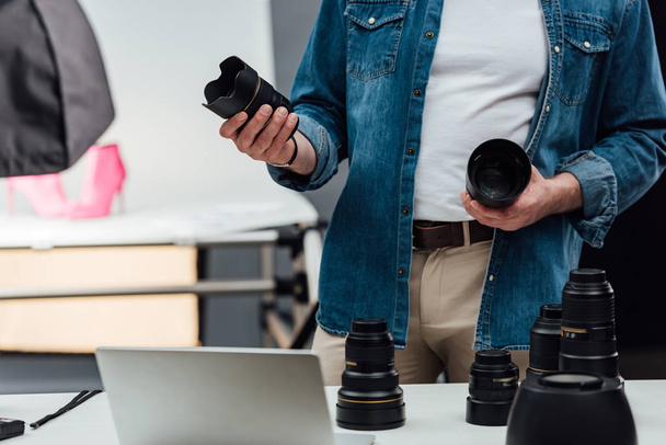 cropped view of man holding camera lenses in photo studio  - Photo, Image