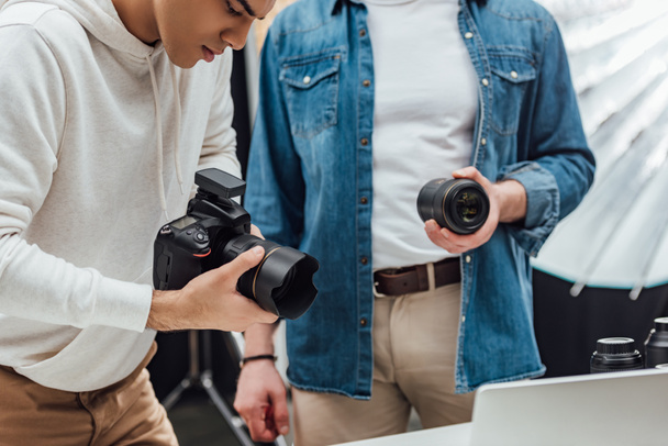 cropped view of art director holding photo lens near photographer  - 写真・画像