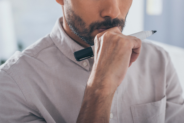 обрізаний вид бородатого змішаного гоночного чоловіка, що тримає маркерну ручку
  - Фото, зображення