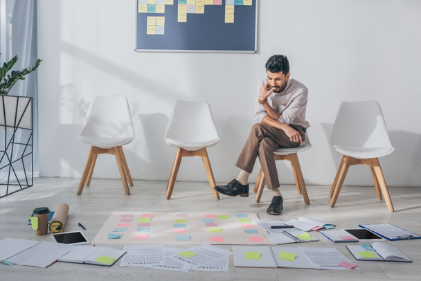 pensive mixed race businessman sitting on chair near sticky notes  - Photo, Image