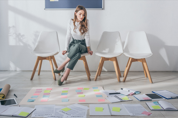 attractive scrum master sitting on chair near sticky notes on floor  - Photo, Image
