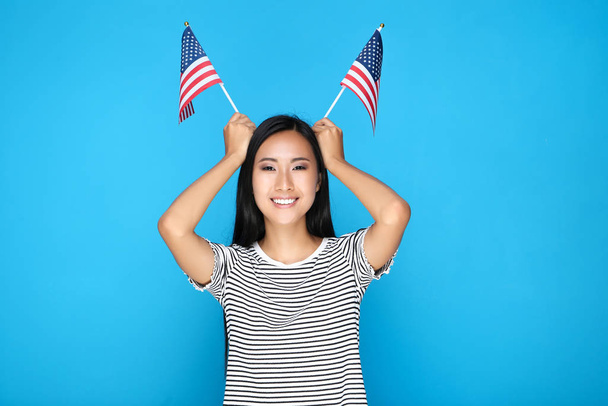 Young woman holding American flag on blue background - Photo, Image