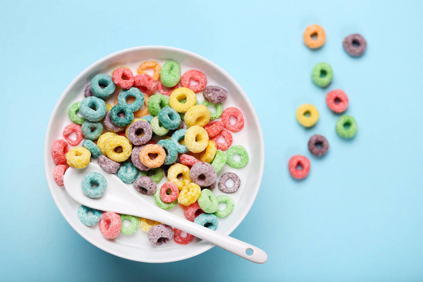 Colorful corn rings in bowl with milk and spoon on blue backgrou - Zdjęcie, obraz