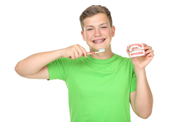 Young man with toothbrush and teeth model on white background - Φωτογραφία, εικόνα