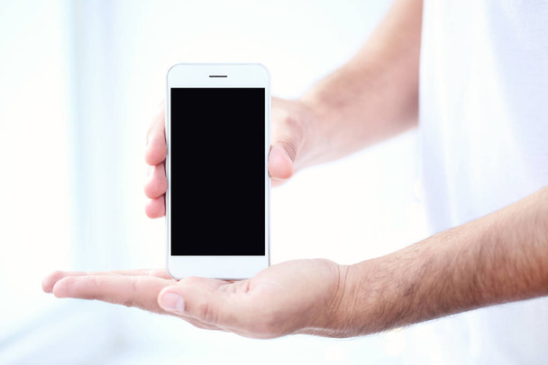 Чоловік тримає в руках мобільний телефон
 - Фото, зображення