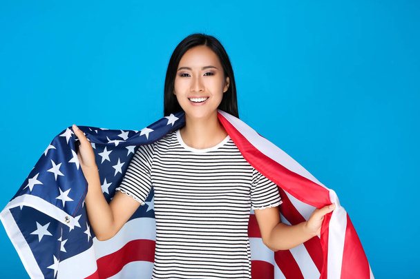 Jonge vrouw met Amerikaanse vlag op blauwe achtergrond - Foto, afbeelding