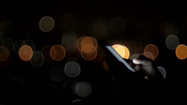 używać smartfona ze światłami bokeh w nocy - Materiał filmowy, wideo