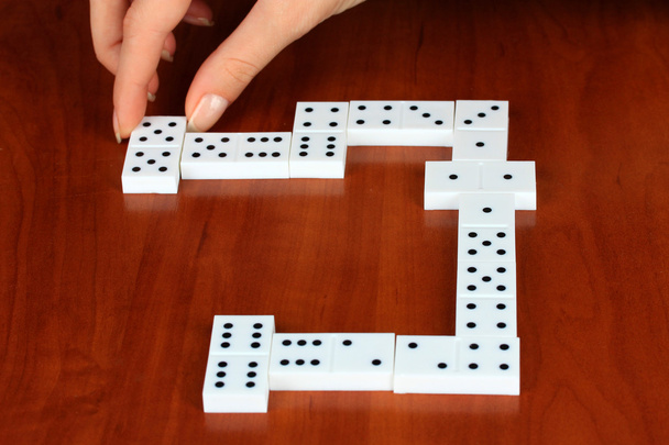 Hand playing domino on wooden background - Fotoğraf, Görsel