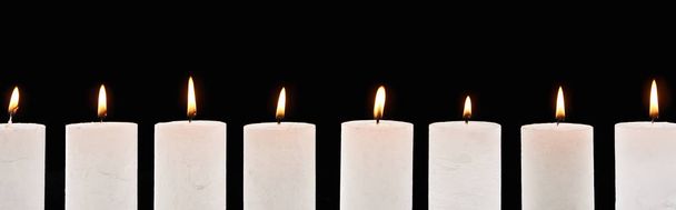 burning white candles glowing in line isolated on black, panoramic shot - Zdjęcie, obraz
