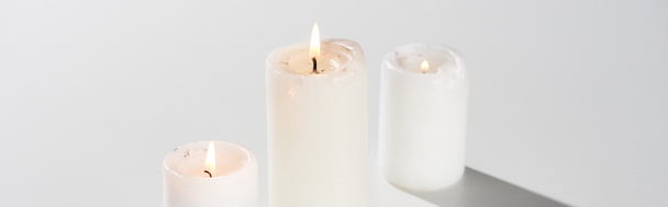 burning candles glowing on white background with shadow, panoramic shot - Foto, Imagem