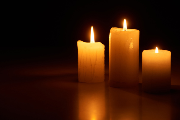 burning candles glowing in dark isolated on black - Photo, Image