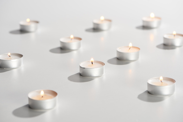 selective focus of burning candles glowing on white surface - 写真・画像