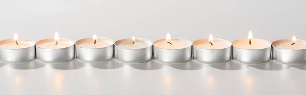 burning candles glowing in line on white background, panoramic shot - Foto, Imagen