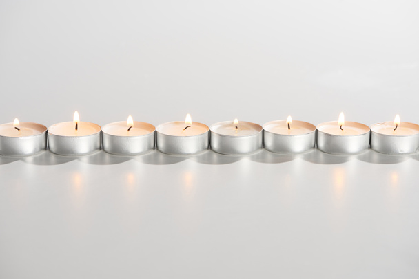 brandende kaarsen gloeiend in lijn op witte achtergrond - Foto, afbeelding