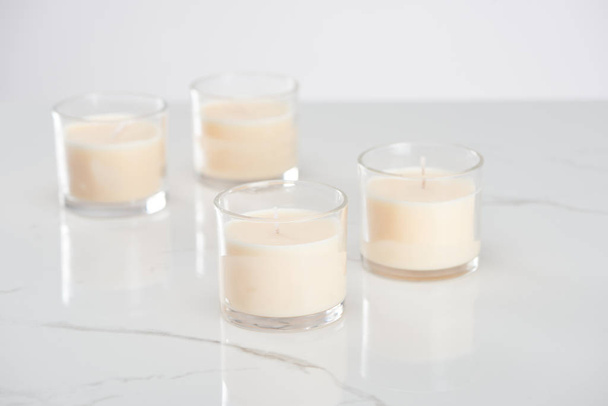 selective focus of white candles in glass on marble white surface - Foto, Imagen