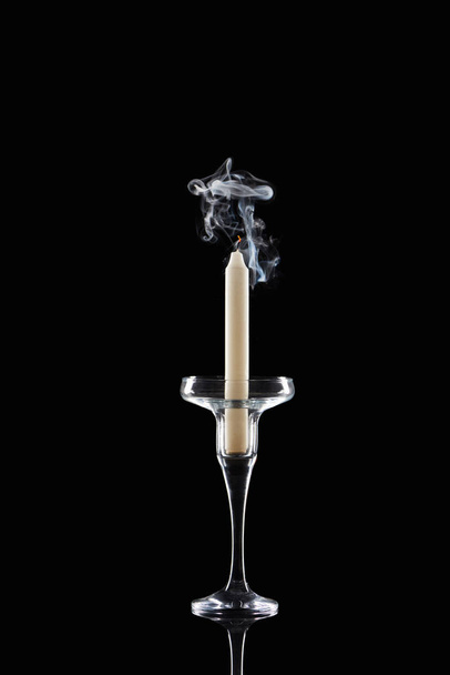 extinct white candle in glass candlestick with smoke on black background - Photo, Image