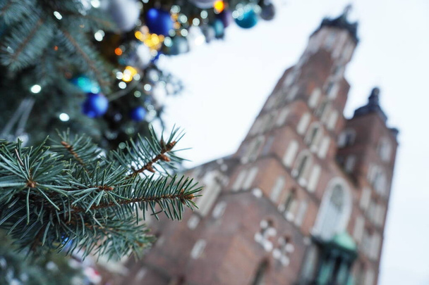 Weihnachtsbaumzweig im Zentrum von Krakau, Polen auf dem Marktplatz im Hintergrund der Kirche. Stadtfeste, Traditionen der Familien zu Weihnachten und Neujahr 2020. - Foto, Bild