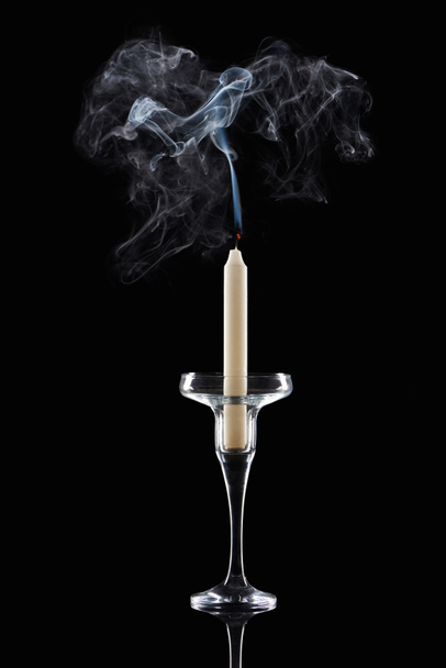 extinct white candle in glass candlestick with smoke on black background - Fotó, kép