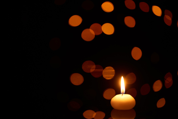 burning candle glowing in dark with bokeh lights on background - Photo, Image