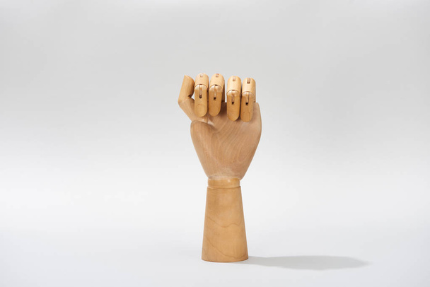 Hand of wooden doll in fist on grey background - Foto, Imagen