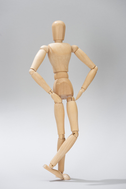 Wooden doll with hands on hips on grey background - Foto, Imagem