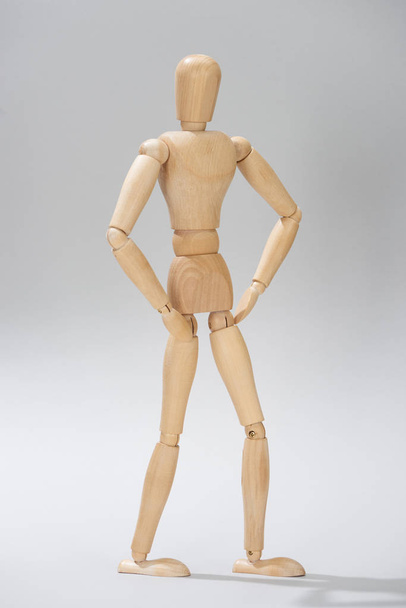 Wooden puppet with akimbo pose on grey background - 写真・画像