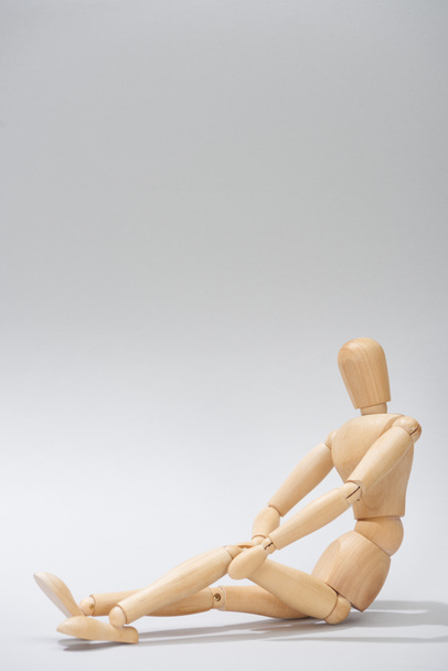Wooden doll with hands on knee on grey background with copy space - Φωτογραφία, εικόνα