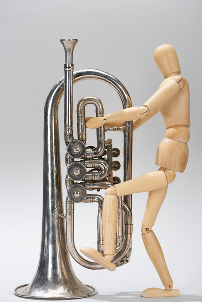 Wooden puppet with alto horn on grey background - Photo, Image