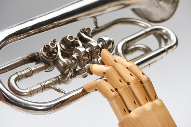 Close up view of wooden hand of doll with alto horn isolated on grey - Photo, Image