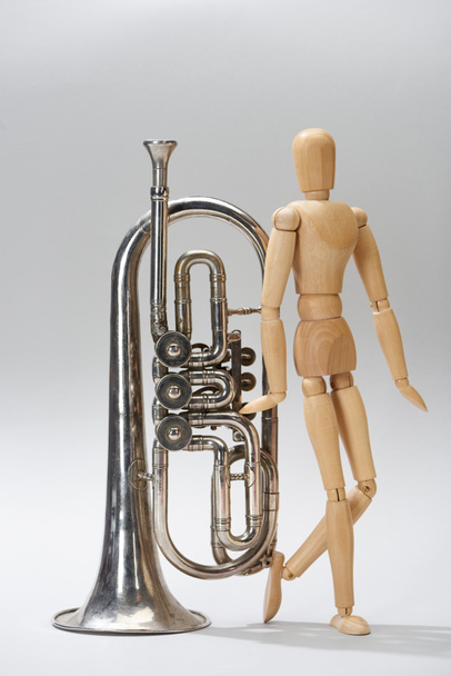Alto horn з дерев'яною лялькою на сірому фоні - Фото, зображення