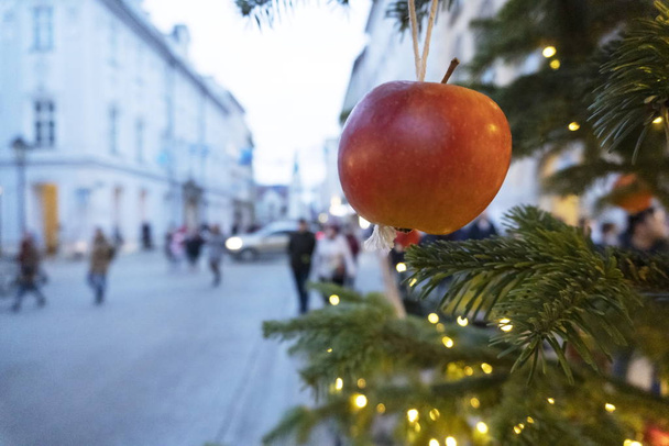 Joulukuusi koristelu omenat ja valoisa seppele, käsintehty. Krakovan mukulakivikadut ovat valmiita jouluun ja uuteen vuoteen. ihmiset hämärtyvät taustalla
 - Valokuva, kuva