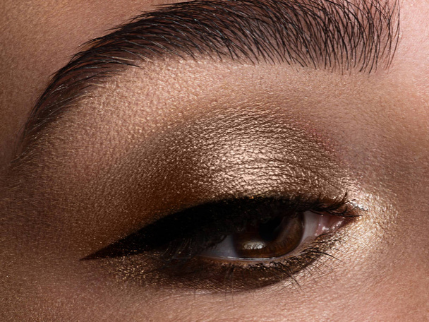 Macro shot. Close-up beauty of woman's eye. Sexy smoky eyes makeup with brown eyeshadows. Perfect strong shape of eyebrows. Make-up and Cosmetics - Φωτογραφία, εικόνα