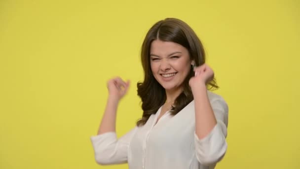 Hey you! Playful happy excited brunette woman in blouse pointing index fingers to camera, making choice with flirtatious look, i want you concept. indoor studio shot isolated on yellow background - Imágenes, Vídeo