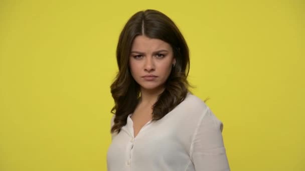 Amazement. Young beautiful woman with brunette hair in blouse turning to camera and looking astonished and unpleasantly surprised, shocked wow face. indoor studio shot isolated on yellow background - Imágenes, Vídeo