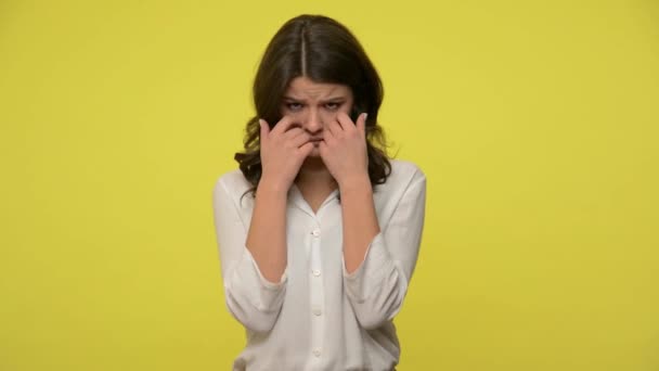 Sad woman with brunette hair in blouse hiding face down in hands and bursting into tears, crying upset about failure, feeling desperate and hopeless. indoor studio shot isolated on yellow background - Кадры, видео