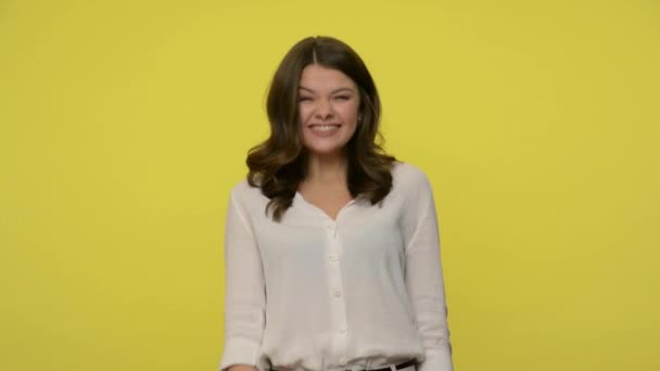 Nice friendly woman with brunette hair in blouse giving hand to handshake and greeting, smiling full of enthusiasm and joy, hospitable sociable hostess. studio shot isolated on yellow background - Imágenes, Vídeo
