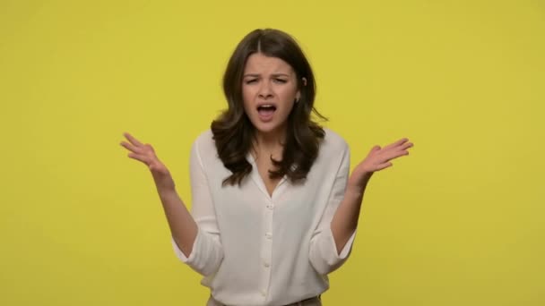 What do you want? Indignant woman with brunette hair in blouse standing with raised hands and annoyed disgruntled expression, having misunderstanding. indoor studio shot isolated on yellow background - Metraje, vídeo