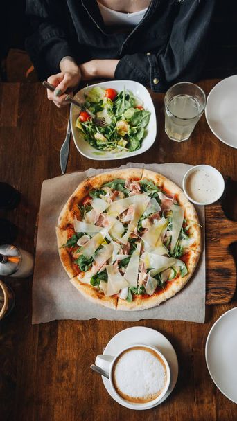 Pizza com presunto de parma, queijo, rúcula, molho em mesa de café rústico
 - Foto, Imagem