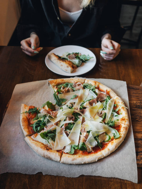Pizza with parma ham, cheese, arugula, sauce in rustic cafe table - Fotografie, Obrázek