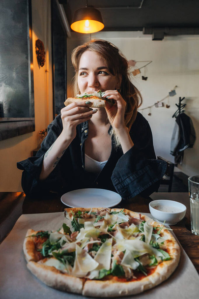 Chica mujer come pizza en acogedora cafetería
 - Foto, imagen