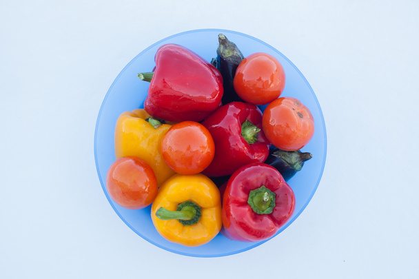 Deep plate with delicious vegetables: peppers, eggplant and tomatoes on white snow - Fotoğraf, Görsel