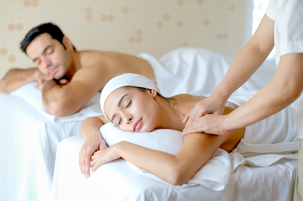 Giovane bella donna godere con massaggio in camera spa con luce del giorno e l'altro uomo sdraiato sul letto accanto a lei
. - Foto, immagini